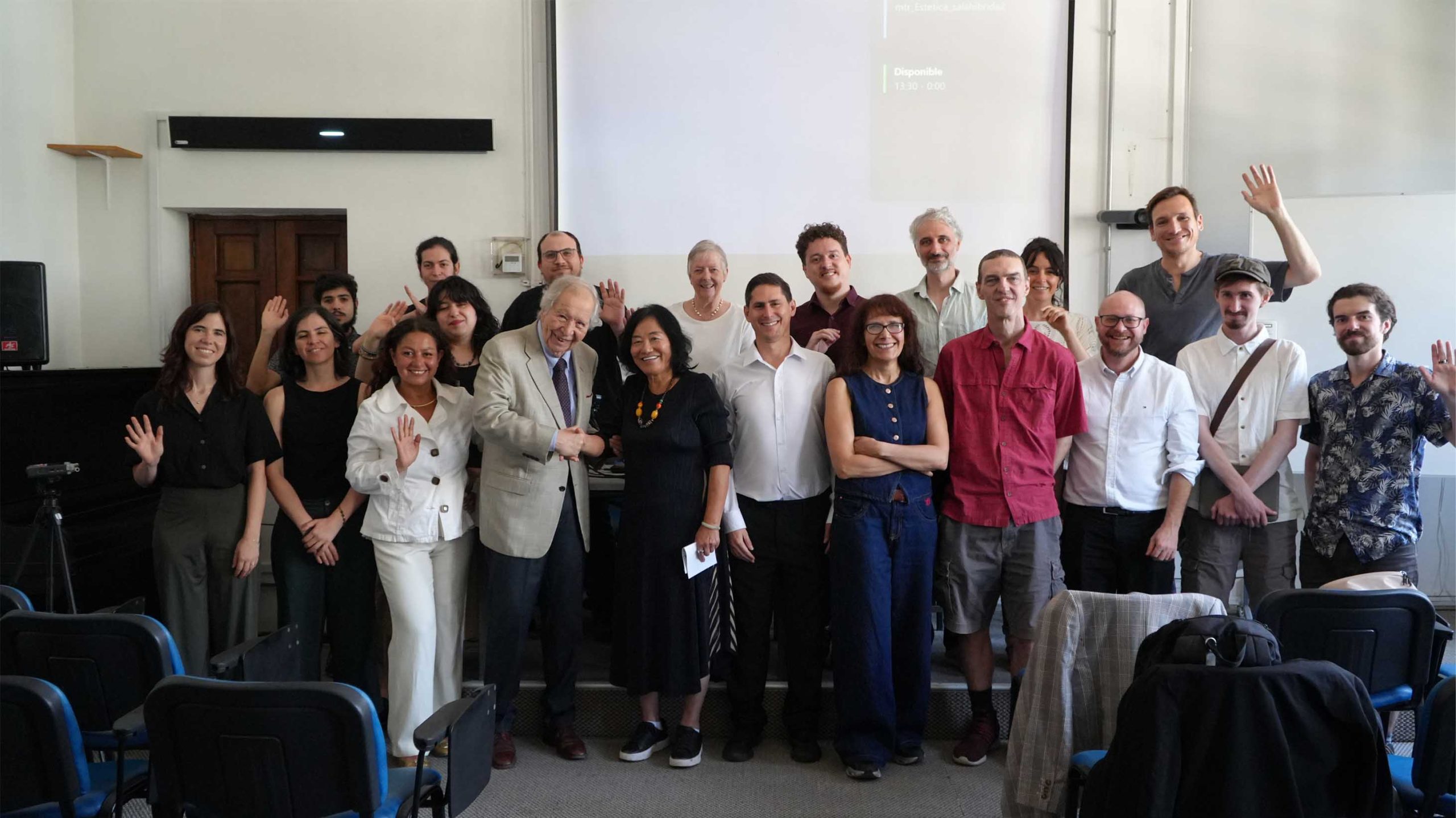 Grupo de personas sonriendo y saludando en un evento.